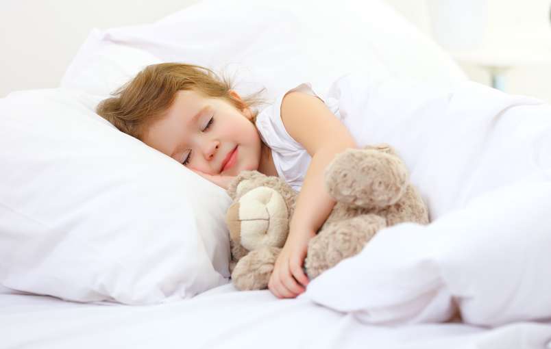 child in bed with toy