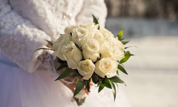 Bride holding a bouquet of white roses at a winter wedding