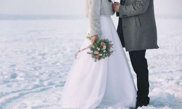 Bride and groom standing in snowy field at their winter wedding