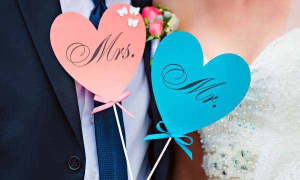 A bride and groom holding mr and mrs signs