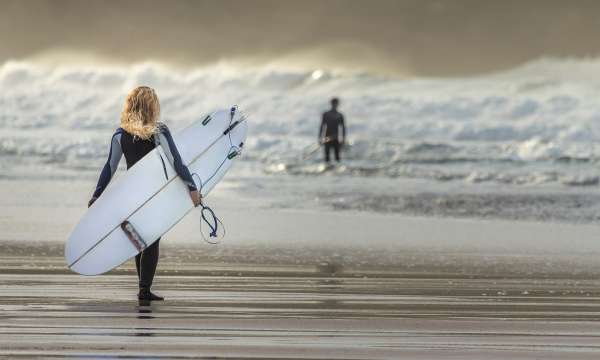 woman walking out to sea with surfboard