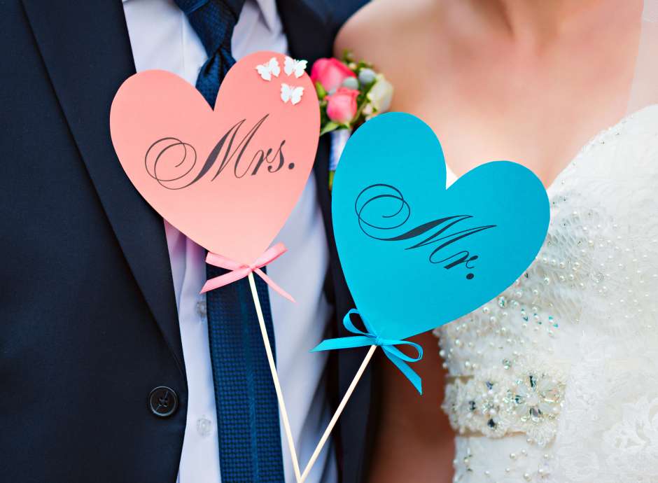 A bride and groom holding mr and mrs signs