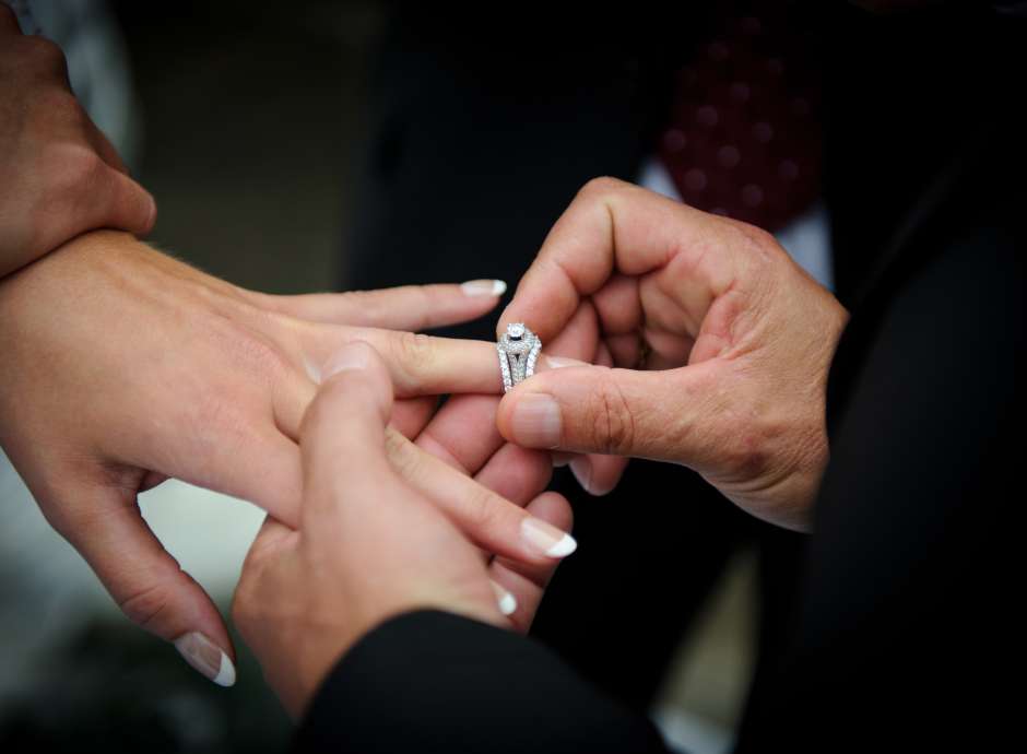A groom putting a wedding ring on his bride's finger