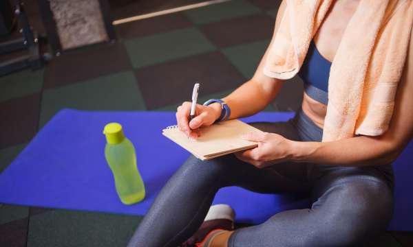 Lady in gym gear writing notes