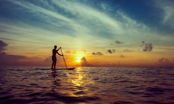 man on sup board at sunset